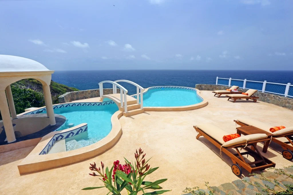 Infinity pool with white loungers and a gazebo, overlooking the ocean on a sunny day in St Lucia