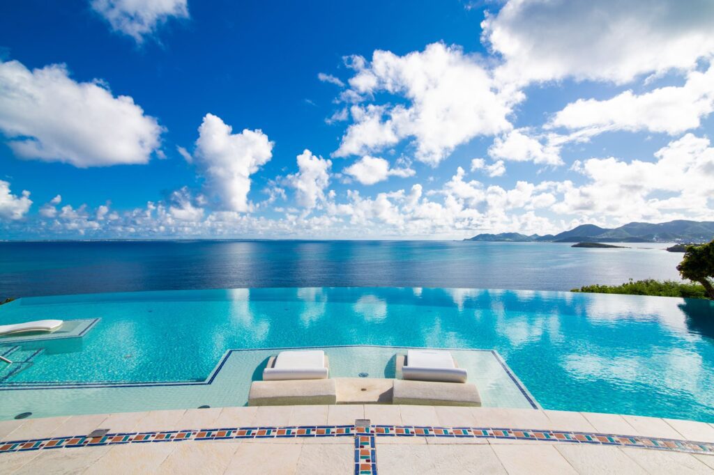 Elegant infinity pool with crystal blue waters and sleek sun loungers, offering a breathtaking view of distant islands and the vast ocean, set in a luxury villa in St Martin