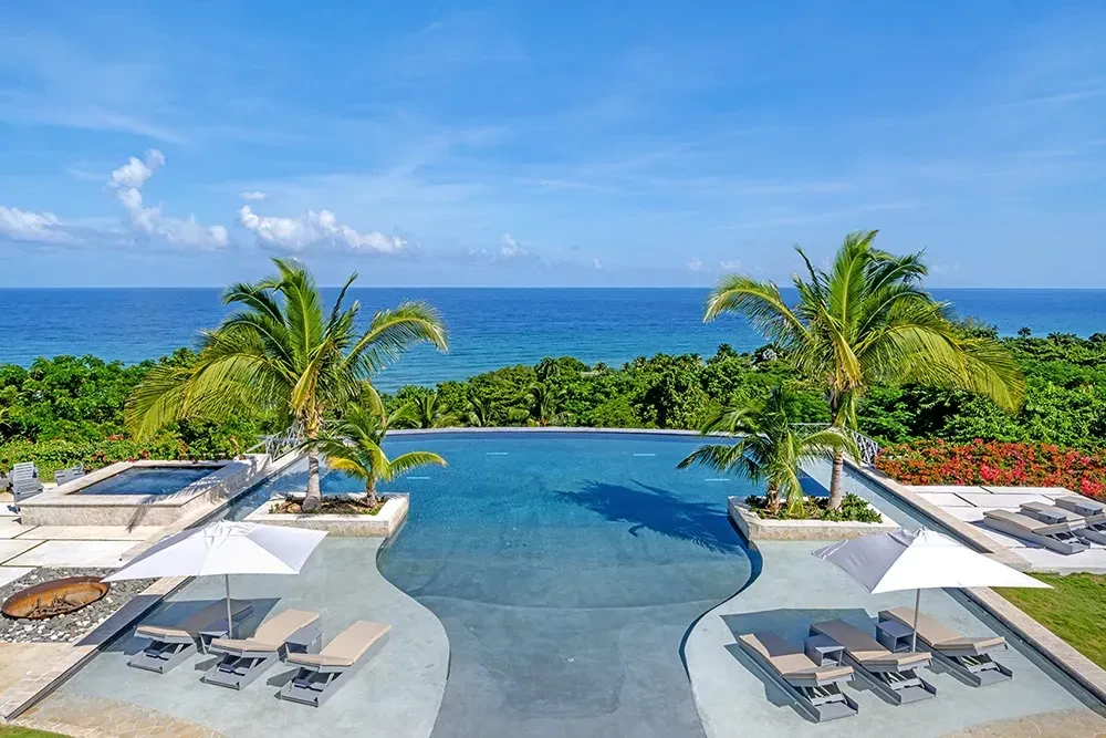 Infinity pool with sun loungers and palm trees overlooking the ocean in Tryall Club