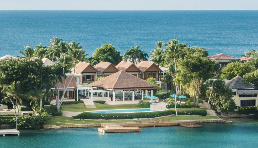 Elegant resort complex with spacious pavilions and lush landscaping along a calm waterfront, featuring luxurious amenities for an upscale vacation experience in Casa de Campo